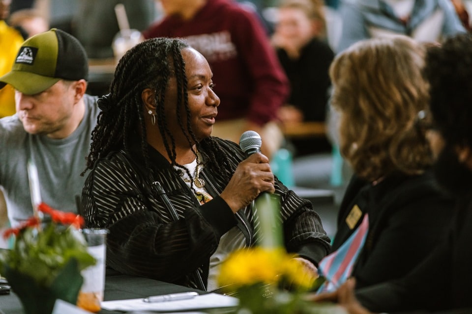 Woman in the crowd talking into a microphone at E & I week.